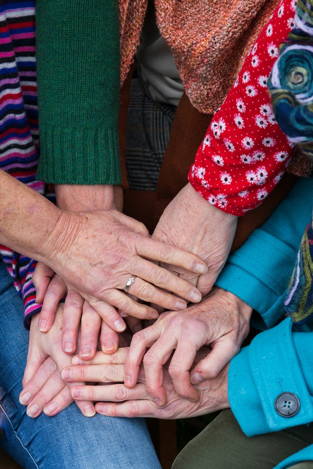 Diverse group stacking hands together in community unity